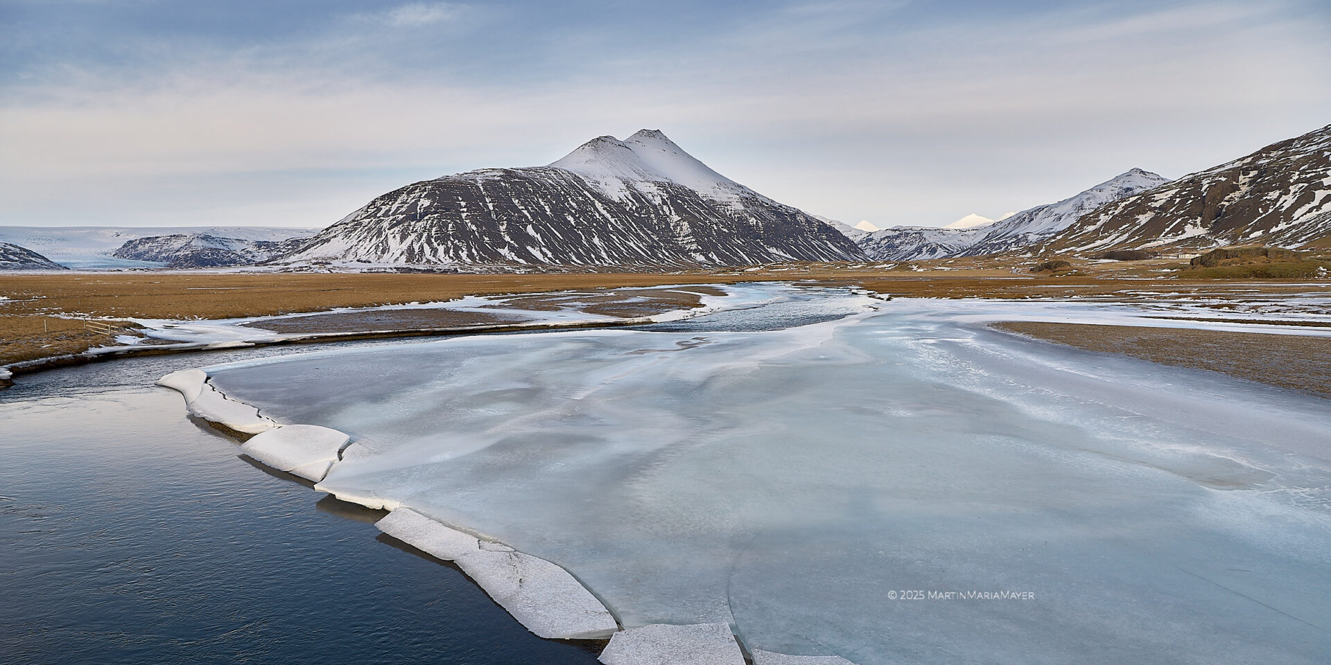 Blick von der Ringstraße Hringvegur auf den im Winter teils vereisten Gletscherfluss Hoffellsá mit dem Berg Gjánúpshorn im Hintergrund im frühen Morgenlicht Islands.