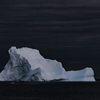 Eisberg in Form eines gekippten Vulkankraters in stiller See vor dem ersten Morgengrauen.