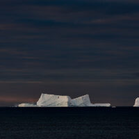 Tafeleisberge auf der Iceberg Alley in der beginnenden Morgenröte leuchten hell am Ende der Nacht in tief dunkler See.